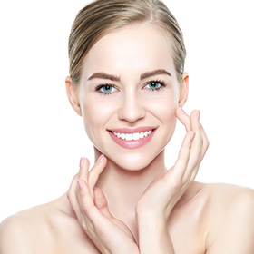 a woman touching her face smiling, showcasing her gummy smile treatment result