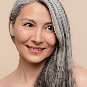 a gorgeous grey haired older woman smiling after a cheek volume restoration treatment