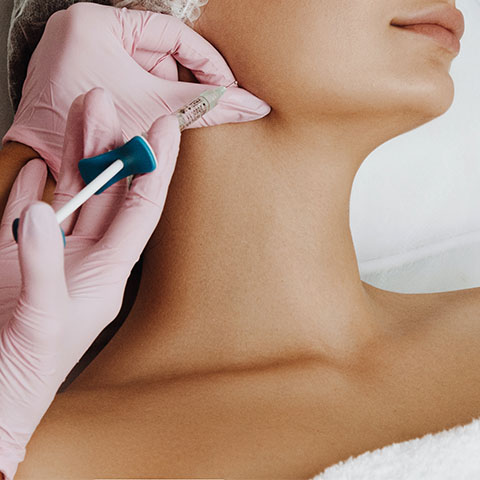 a woman receiving a dermal filler injection to her jawline